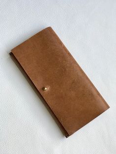 a brown leather notebook with a button on the cover sitting on top of a white surface