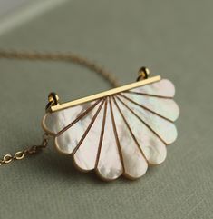 This beautiful Art Deco pendant necklace is pure Mother of Pearl which has been carved into a simple scalloped semi-circle shape.  The pearl has an incredible sheen and take on a subtle glow when they catch the light.  The pendant is finished with a delicate and fine gold plated chain.   This necklace is available in a choice of chain lengths.  Please refer to our illustrated guide for a better idea of how they might look when worn.   🖤 FASTER SHIPPING 🖤 Need this fast? We offer a Faster Shipp Mother Of Pearl Pendant Jewelry Gift, Gold Mother Of Pearl Flower Pendant Jewelry, Mother Of Pearl Pendant Jewelry For Gifts, Delicate Mother Of Pearl Jewelry For Wedding, White Shell-shaped Pearl Pendant Jewelry, White Shell-shaped Necklace For Gift, Shell-shaped Gold Jewelry For Wedding, White Shell-shaped Necklace For A Gift, White Sterling Silver Shell Necklace For Gift