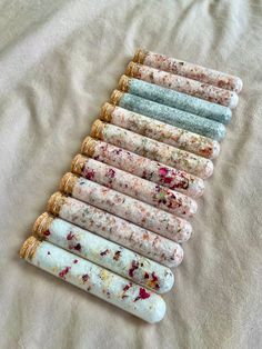 seven different colored rolling stones lined up in a row on top of a white sheet