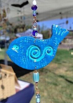 a wind chime with a blue bird on it's side and beads hanging from the top