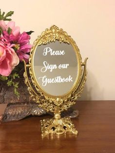 a mirror sitting on top of a wooden table next to a vase filled with flowers