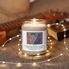 a lit candle sitting on top of a wooden table next to a string of lights