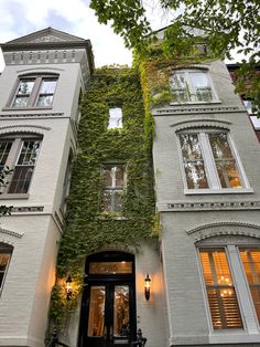 an old building with ivy growing on it's side and windows above the door