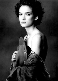 a black and white photo of a woman holding a hat