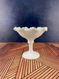 a white vase sitting on top of a wooden table