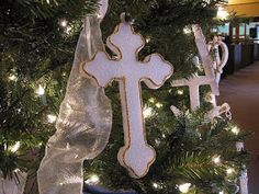 a christmas tree decorated with white and gold decorations, including a cross ornament