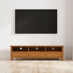 an empty room with a television mounted on the wall and drawers below it, in front of a white painted wall