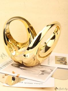 a shiny gold object sitting on top of a pile of papers next to a pair of scissors