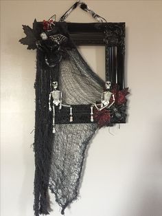 a black frame with skeleton decorations hanging on the wall next to a white wall and a mirror