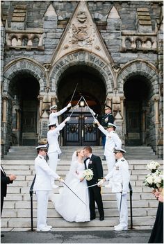 a bride and groom standing on steps with their hands in the air as they kiss