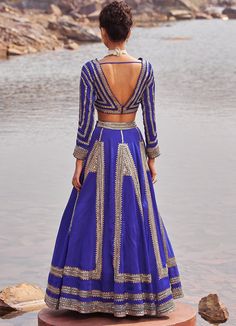 Step into the spotlight with the Ink Blue and Gold Satin Sequinned Lehenga ! Crafted with meticulous attention to detail, this bold and beautiful lehenga features exquisite hand embellishments. The inky blue color will make you stand out at any summer wedding, reception, or sangeet ceremony. The lehenga is paired with an embroidered V-neck blouse in organza satin with gorgeous full sleeves. To add a touch of elegance, the ensemble is complemented by a stunning handwork soft net dupatta. Embrace timeless style and make a statement with this stunning blue sequinned lehenga. Composition : Organza, Satin, Soft Net, Lining - Shantoon Care: Dry Clean Only and Vacuum Storage This product can be customized for sleeves, length of blouse and neckline Delivery : 4-6 weeks as the product is hand craft Traditional Hand Embellished Blue Choli, Blue Hand Embellished Sharara For Reception, Blue Hand Embellished Choli For Reception, Blue Hand Embellished Fitted Sharara, Blue Hand Embellished Floor-length Choli, Blue Hand Embellished Choli For Party, Blue Hand Embellished Traditional Gown, Traditional Blue Hand Embellished Gown, Festive Blue Hand Embellished Choli