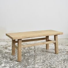 a wooden bench sitting on top of a white and gray carpeted floor next to a wall