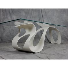 a glass and metal coffee table with curves on the top, sitting on a gray background