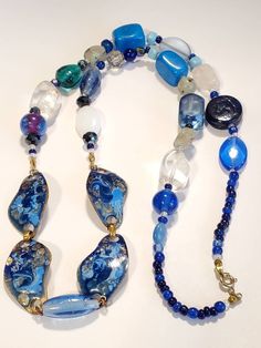 "Beautiful collection of glass and stones. The array of blue colors give an elegance with this necklace. Center pieces of pendant are 4 abstract shape copper metal, with beautiful colors of dark blue,and light blue enamel with exposed copper, in a high gloss finish. Each metal piece measuring 1.5\" wide. Along with clear and frosted large beads, connecting to blue clear glass beads. Several agate gemstone beads Accent beads of multifaceted design, along with accent blue beads Turquoise large blu Blue Polished Beads Costume Jewelry, Costume Jewelry Necklaces With Polished Czech Glass Beads, Costume Jewelry Necklaces With Czech Glass Polished Beads, Turquoise Glass Necklaces With Gemstone Beads, Unique Long Glass Necklace, Blue Jewelry For Gifts, Blue Polished Beads Jewelry, Blue Glass Bohemian Beaded Necklaces, Blue Glass Beaded Bohemian Necklace