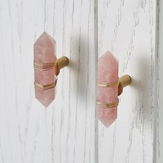 two pink door knobs with gold handles on a white painted wooden door, one has a rose quartz stone and the other is brass