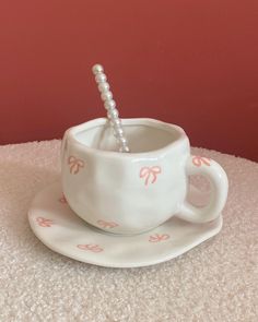 a cup with a straw in it sitting on a saucer next to a pink wall