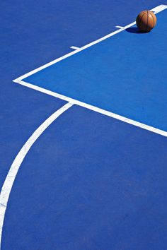 a basketball sitting on top of a blue court next to a white line in the middle