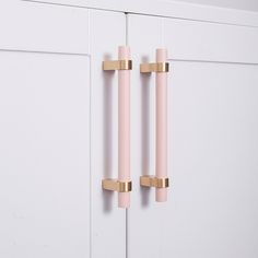 two pink and gold handles on white cabinets