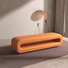 an orange couch sitting on top of a rug next to a lamp and window sill