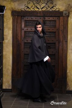 a man in a black robe standing next to a wooden door