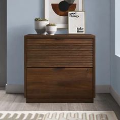 a wooden dresser sitting in the corner of a living room next to a painting on the wall