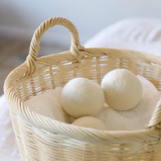 three white balls in a basket on a bed