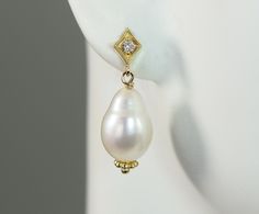 Lovely tear drop shaped baroque freshwater pearls drop from a diamond set in a diamond shaped post setting all in 14k yellow solid gold. Pearl is the birthstone for June and the 3rd and 30th wedding anniversary gemstone. Diamond is the birthstone for April and the 10th and 60th wedding anniversary gemstone. The natural color cultured freshwater pearls measures 12 x 9.6 mm tear drop shape The natural diamonds total weight is .05 carats G-H color VS2 clarity Metal is 14k yellow gold The total leng Luxury Gold Plated Pearl Drop Danglers, High Luster Drop Pearl Earrings For Anniversary, Classic Diamond Teardrop Pearl Earrings, Classic Teardrop Diamond Pearl Earrings, High Luster Teardrop Pearl Earrings, Classic Pear Shaped Drop Gift, Classic Pear-shaped Drop Gift, White Diamond Teardrop Pearl Earrings, White Teardrop Diamond Pearl Earrings