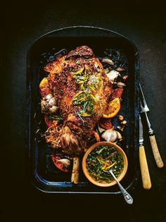 a roasting pan with meat, vegetables and sauces on the side next to a spatula