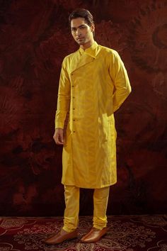 Yellow side cut kurta with pintuck panels patched together and adorned with gold buttons. Comes along with churidar.
Components: 2
Pattern: Pintuck
Neckline: Stand Collar
Sleeve Type: Full Sleeves
Fabric: Cotton Silk
Color: Yellow
Other Details: 
Closure: Front buttons
Occasion: Sangeet - Aza Fashions Gold Naqshi Straight Kurta, Bollywood Style Bandhgala With Straight Kurta, Designer Straight Kurta Bandhgala For Festivals, Designer Bandhgala For Festivals With Straight Kurta Style, Cotton Silk Bandhgala For Designer Wear, Yellow Chanderi Kurta With Naqshi Detail, Festival Chanderi Kurta With Naqshi, Unstitched Chanderi Bandhgala Straight Kurta, Yellow Naqshi Chanderi Kurta