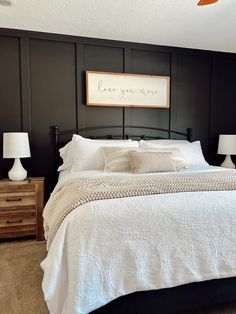 a bedroom with black walls and white bedding