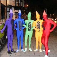 five people in bodysuits standing next to each other on a sidewalk at night