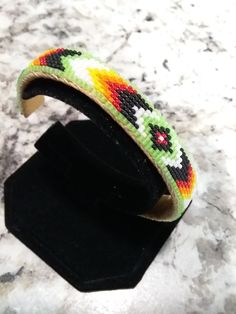 a close up of a bracelet on a black display stand with a marble surface in the background