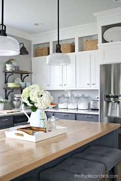 a kitchen with white cabinets and gray stools in front of a counter top that has flowers on it