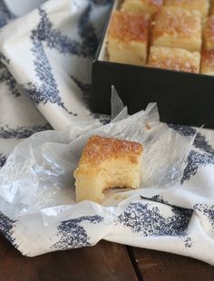 a piece of cake sitting on top of a white and blue cloth next to a box