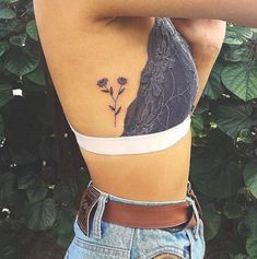 the back of a woman's stomach with flowers on it and an arrow tattoo