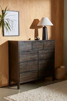 a wooden dresser sitting next to a lamp on top of a white carpeted floor