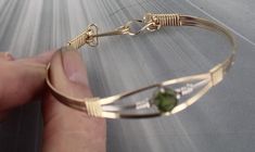 THE BEAUTY OF PERIDOT  THIS BRACELET IS WATER PROOF AND TARNISH RESISTANT  ELEGANT PERIDOT    GEMSTONE  BANGLE BRACELET IN  14KT ROLLED GOLD  HAS ONE 8MM STONE IN IT  HANDCRAFTED IN 14KT ROLLED GOLD  IN A UNIQUELY DESIGNED SETTING UNIQUE HANDCRAFTED PIECE THAT WILL GET YOU NOTICED! LIGHTWEIGHT AND EASY TO WEAR SIZE ----- SIZE 6 TO 8 BRACELET IS 1/2 OF AN INCH WIDE ON THE SIDES BRACELETE IS  1/2   INCH WIDE IN FRONT iTS COMFORTABLE HEAVY DUTY HOOK AND CATCH MAKES IT EASY TO TAKE ON AND OFF AN EYE CATCHING PIECE! WEAR IT CASUAL OR FORMAL 7 THINGS TO KNOW ABOUT 14KT ROLLED GOLD #1. 14 Kt Rolled gold wire is also called gold filled wire------This gold wire was used extensively in the 1800's and early 1900s. It is not used very much today its too expensive.  It is durable that is it is very, ve Sculpted Jewelry, Make Up Gold, Gemstone Bangle Bracelets, Wire Wrapped Bangles, Peridot Bracelet, Gemstone Bangle, Wire Wrapped Bracelet, Bracelet Gemstone, Peridot Gemstone