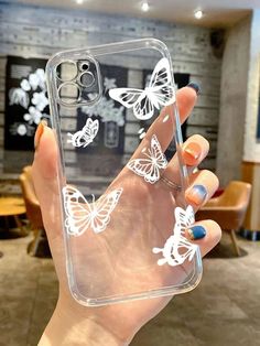 a woman holding up her phone case with butterflies on it