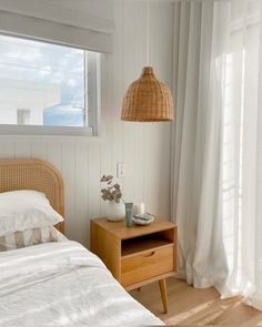 a bed sitting next to a window in a room with white walls and wooden floors