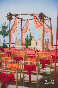 an outdoor wedding set up with red and orange sashes