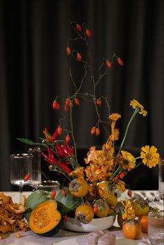 an arrangement of fruit and flowers on a table