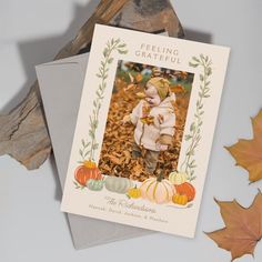 a greeting card with an image of a baby in the fall leaves and pumpkins