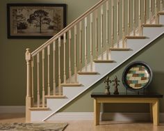 a white stair case next to a table with a clock on it and a painting