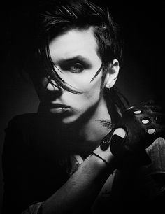 a man with black hair and piercings on his face holding a glove in one hand