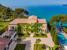 an aerial view of a large house next to the ocean with trees and shrubs surrounding it