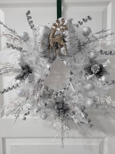 a christmas wreath hanging on the front door with silver ornaments and a giraffe