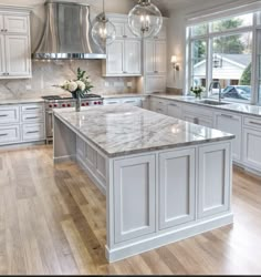 a large kitchen with white cabinets and marble counter tops, an island in the middle