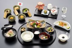 a black table topped with lots of different types of dishes and bowls filled with food