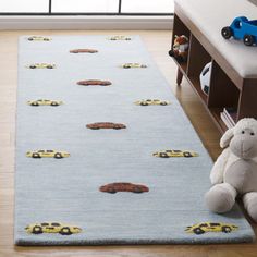 a blue rug with cars on it and a teddy bear sitting in front of it