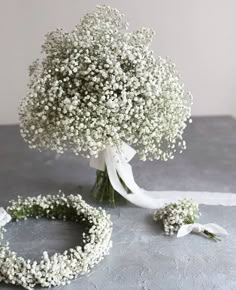 a bouquet of baby's breath sits on a table next to a wedding ring